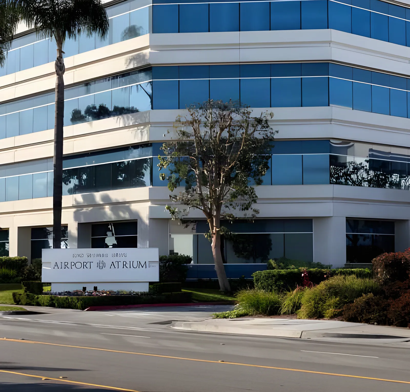 The four-story glass Airport Atrium office building at 2780 Skypark Drive with palm trees